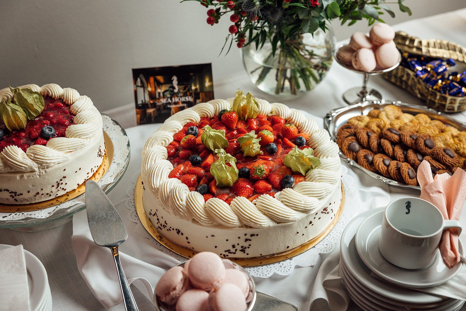 Juhlatilaisuuksien kakkupöytä, mansikkatäytekakku, pikkuleipiä, konvehteja ja samppanjaa klassisessa Ravintola Sea Horsessa Helsingin Ullanlinnassa Festive dessert table with strawberry cake, biscuits, chocolates and champagne at classic restaurant Sea Horse, Ullanlinna, Helsinki