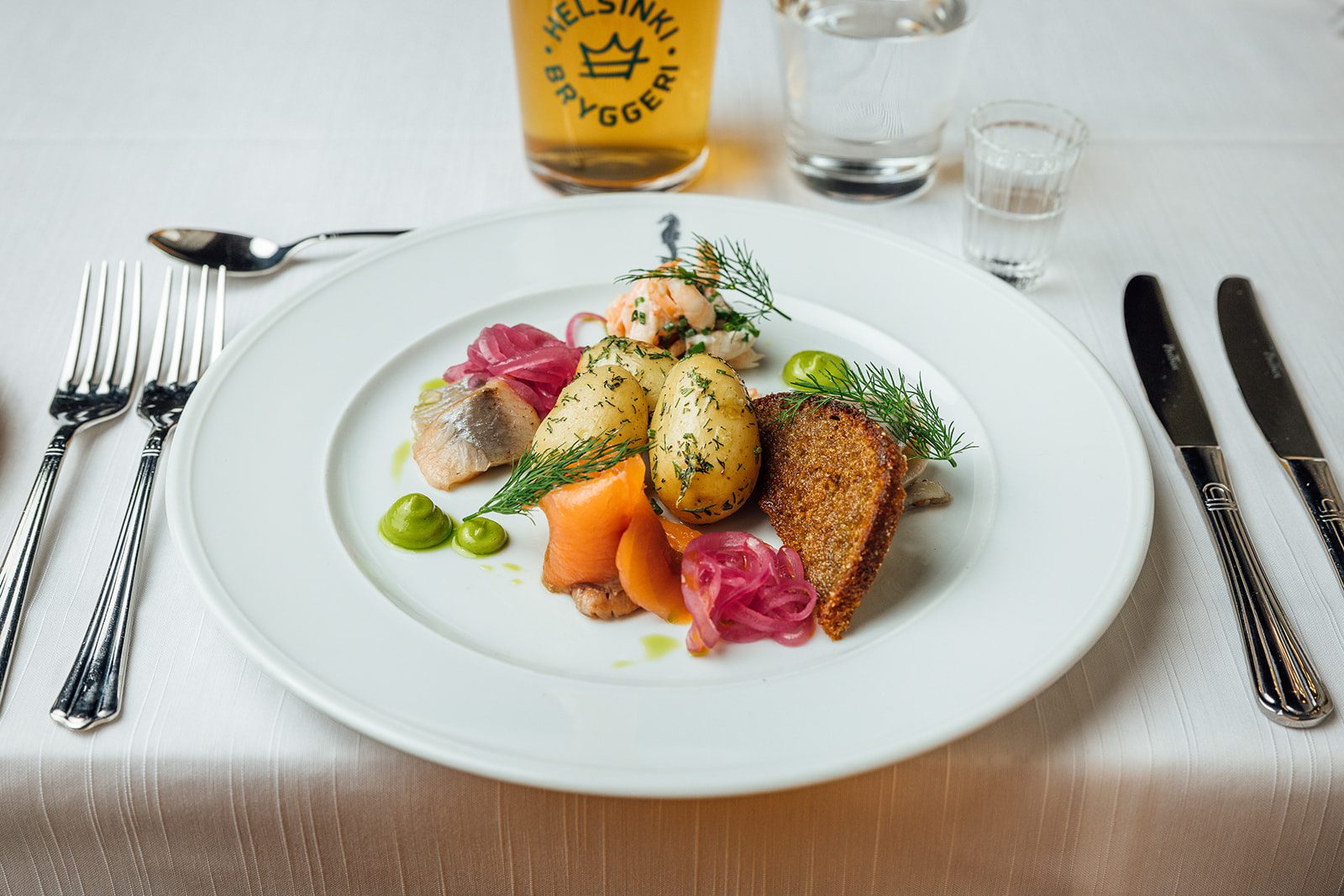 Kalalautanen, jossa graavattua lohta, skagenröraa, mustaherukka- ja fenkolisilakoita ja keitettyjä perunoita A seafood plate with cured salmon, skagen, blackcurrant and fennel pickled herring, and boiled potatoes